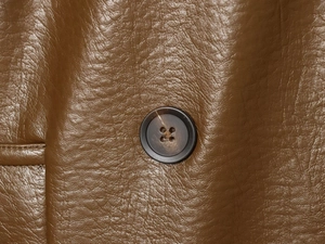 Macro texture de cuir synthétique marron avec grainage et détail de bouton rond