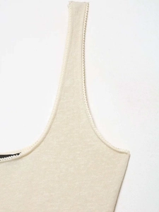 Detail of beige knitted camisole featuring delicate scalloped edges and fine texture