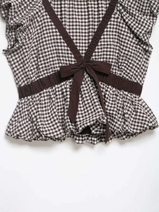 Detail of gingham top with V-neckline, brown ribbon trim and decorative bow accent
