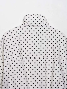 Détail du col montant et de l'imprimé à pois noirs sur tissu d'été blanc léger