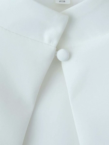Detail of white blouse featuring a mandarin collar with fabric button and a V-neck cut