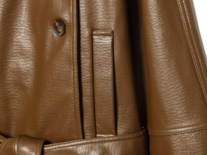 Détail rapproché de la texture du similicuir marron foncé avec bouton et coutures