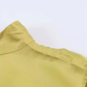 Detail der senfgrünen Satinbluse mit Twill-Struktur und Stehkragen-Nähten