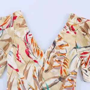 Detail of V-neckline and puff sleeves on a printed dress with abstract feather patterns