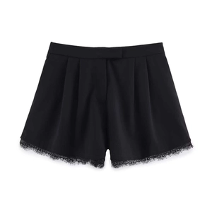 Detail of high-waist black suit shorts featuring refined eyelash lace trim and pleated hem