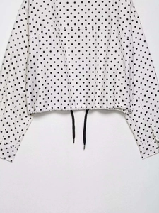 Détail de la blouse à pois avec cordon de serrage ajustable à l'ourlet et taille élastique