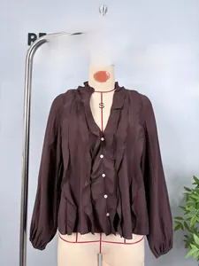 Detail of elegant brown chiffon shirt with tiered ruffles and pearl buttons on V-neckline