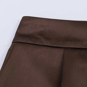 Macro shot of dark brown high-waisted shorts with lace patchwork and pleat details