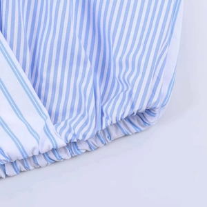 Close-up of blue striped poplin shirt with crossover design and elastic hem detail