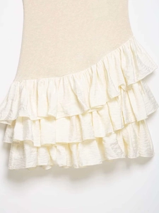 Detail shot of the layered beige fabric and creamy white tiered ruffles on the dress