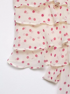 Détail du tissu en mousseline beige à pois magenta avec des volants multicouches