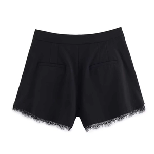 Detail of black dress shorts featuring delicate eyelash lace trim and back welt pockets