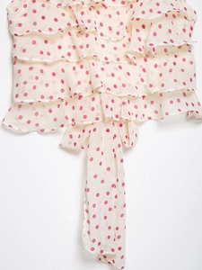 Détail du tissu en mousseline à pois avec des volants superposés et des liens élégants