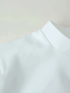 Detail of a white mandarin collar top showing smooth fabric texture and shoulder seams