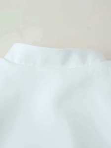 Detailed view of a white stand-up collar blouse featuring minimalist tailored design