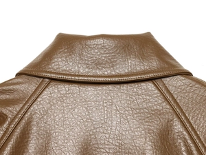 Détail de la texture en similicuir marron et des coutures sur la veste courte vintage