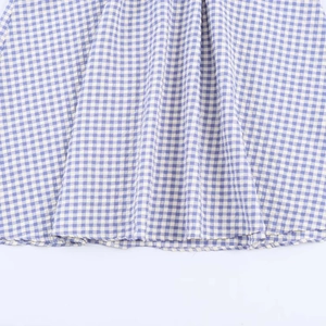 Close-up of blue and white gingham midi dress hem with neat stitching and fine texture