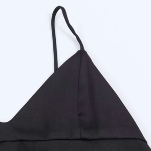 Detail of thin spaghetti straps and silky satin texture on a black asymmetrical camisole