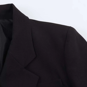 Detailed view of the lapel and shoulder of a black suit jacket with lace stitching