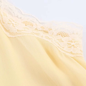 Close-up of elegant light yellow satin fabric with delicate floral white lace trim