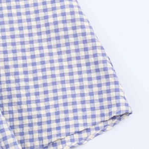 Detail of blue and white gingham fabric with high-quality stitching on a summer midi dress