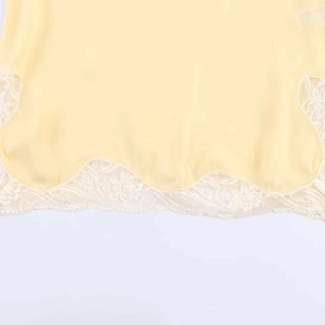 Pale yellow satin camisole with delicate white floral lace trim and wavy split hemline