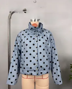 Detail of light blue polka dot jacket with stand collar, drawstring, and button closure