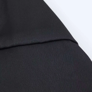 Close-up detail of smooth black satin fabric and high-quality stitched seam on clothing
