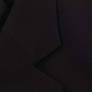 Detailed close-up showing the lapel tailoring and fine woven texture of black blazer jacket