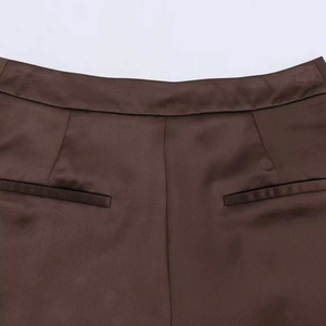 Detail of high-waist dark brown trousers featuring symmetrical welt back pockets