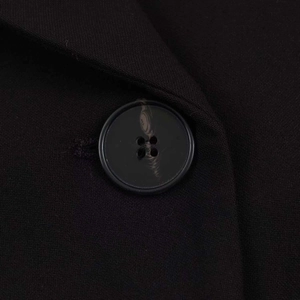Macro shot of detailed fabric texture and a unique headphone-patterned button on a blazer