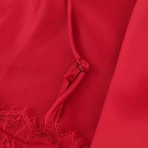 Detail of red satin fabric with delicate lace trim and adjustable shoulder strap