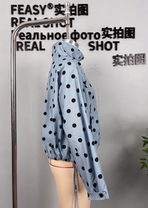 Detailed close-up of light blue polka dot jacket with high collar and elastic cuffs