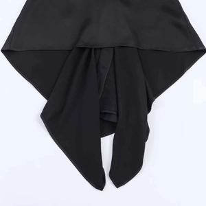 Detail shot of black asymmetrical satin camisole featuring decorative straps and hem