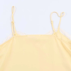 Close-up of pale yellow satin camisole featuring delicate white lace trim on neckline