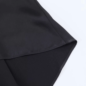Detail of the curved hemline and smooth satin texture on this black camisole top