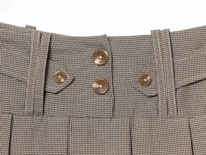 Detail of the waist with brown houndstooth pattern and double amber button closure