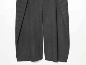 Détail d'un pantalon large gris foncé avec de fines rayures verticales blanches
