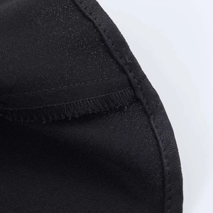 Close-up of fine stitching and satin fabric texture on an asymmetric black camisole