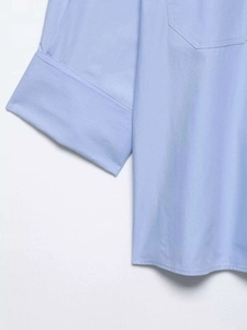 Vue détaillée de la chemise bleu clair montrant la texture du tissu et coutures des poignets