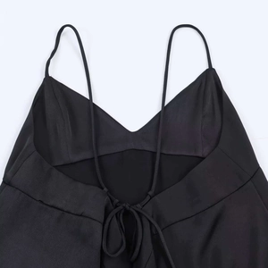 Detail view of black satin camisole featuring thin straps and back lace-up design