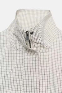 Détail du col montant et du zip métallique sur la veste courte à carreaux minimaliste