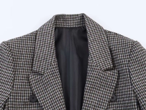 Detail view of houndstooth plaid blazer lapel with textured fabric and buttons