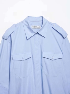 Détail d'une chemise bleu clair avec des épaulettes boutonnées et des poches de poitrine
