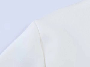 Close-up detail of neat stitching on shoulder and sleeve of a white chiffon blouse
