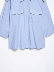 Détail de la chemise bleu clair avec poches poitrine symétriques et rabats à boutons
