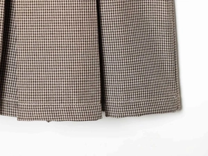 Detail of vintage houndstooth pattern fabric with pleats and fine stitching on skirt