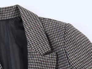 Detail of a plaid blazer featuring classic houndstooth pattern and smooth black lining