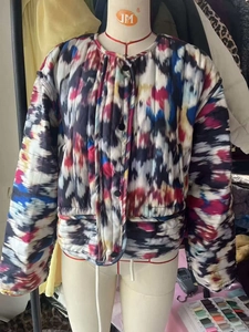 Détail d'une doudoune matelassée avec imprimé tie-dye abstrait et boutons à pression