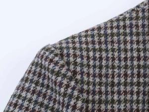 Macro detail of plaid tweed blazer showing woven texture and houndstooth pattern fabric
